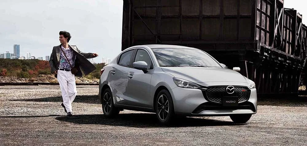 Mazda 2 Sedán color Gris Aéreo, escena editorial en entorno industrial